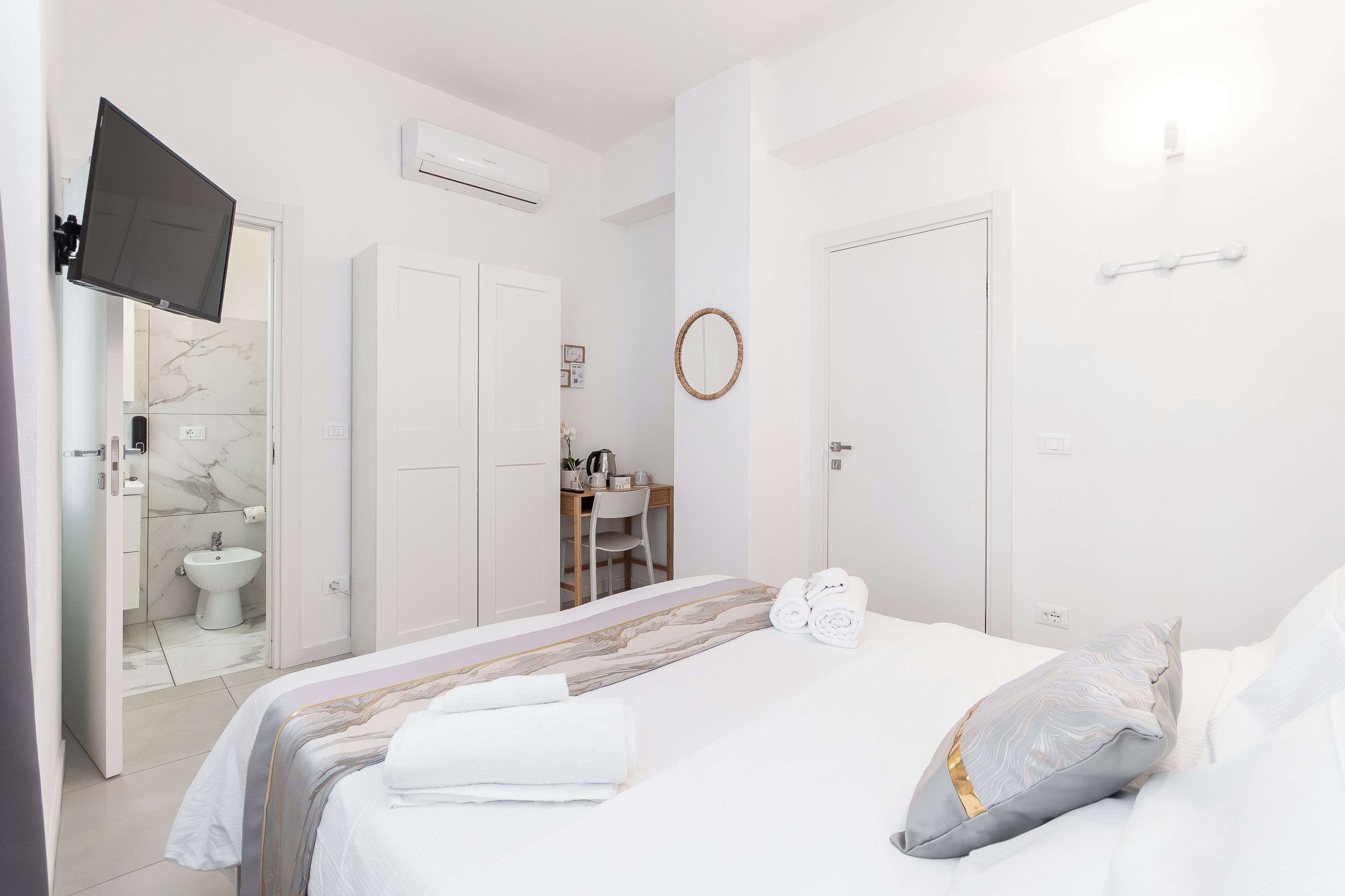 Una habitación de hotel con cama, escritorio, silla, televisor y baño.
