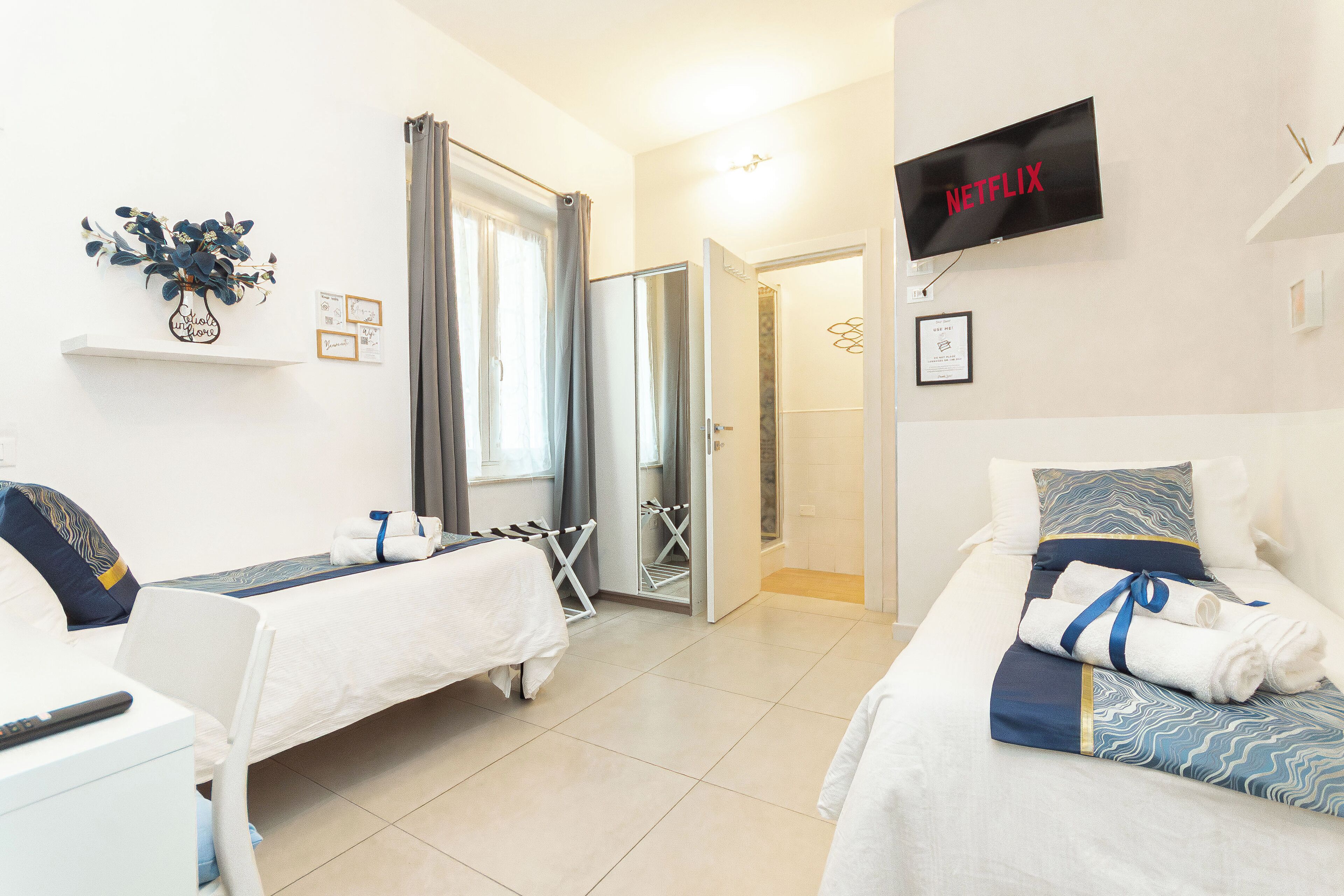 A hotel room with two beds, a TV, a shower, and a small desk.