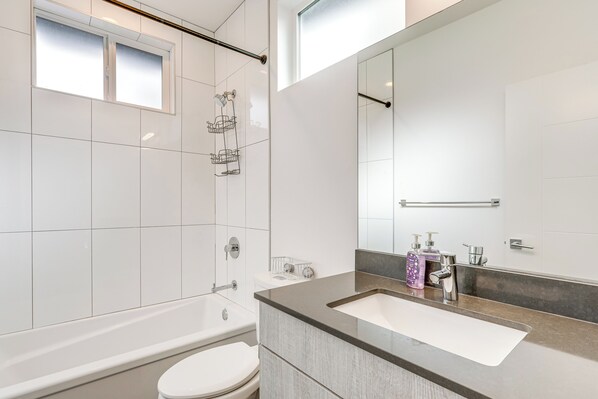 Een moderne badkamer met een bad, toilet en wastafel.