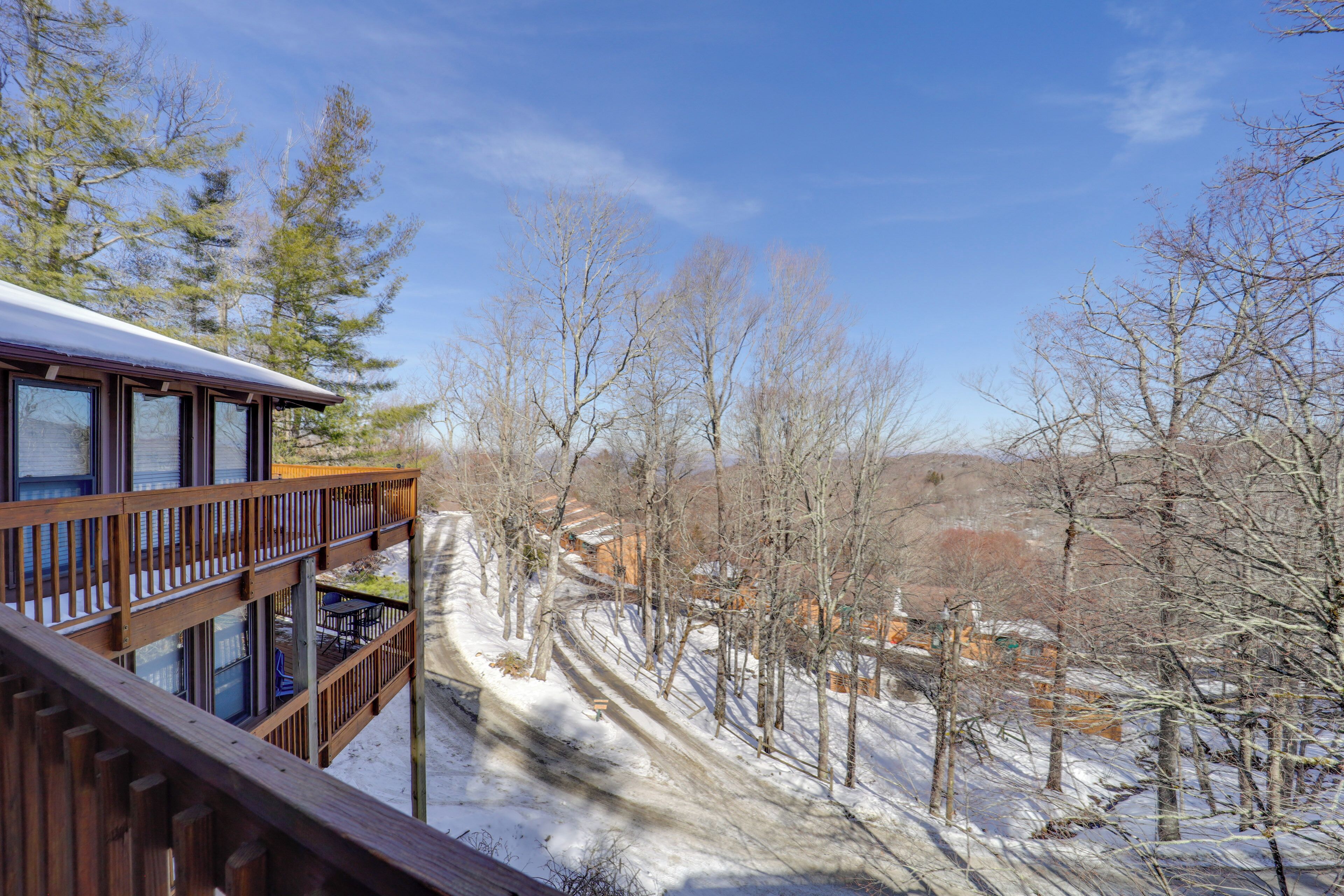 A wooden deck with a view of a snowy landscape and trees.