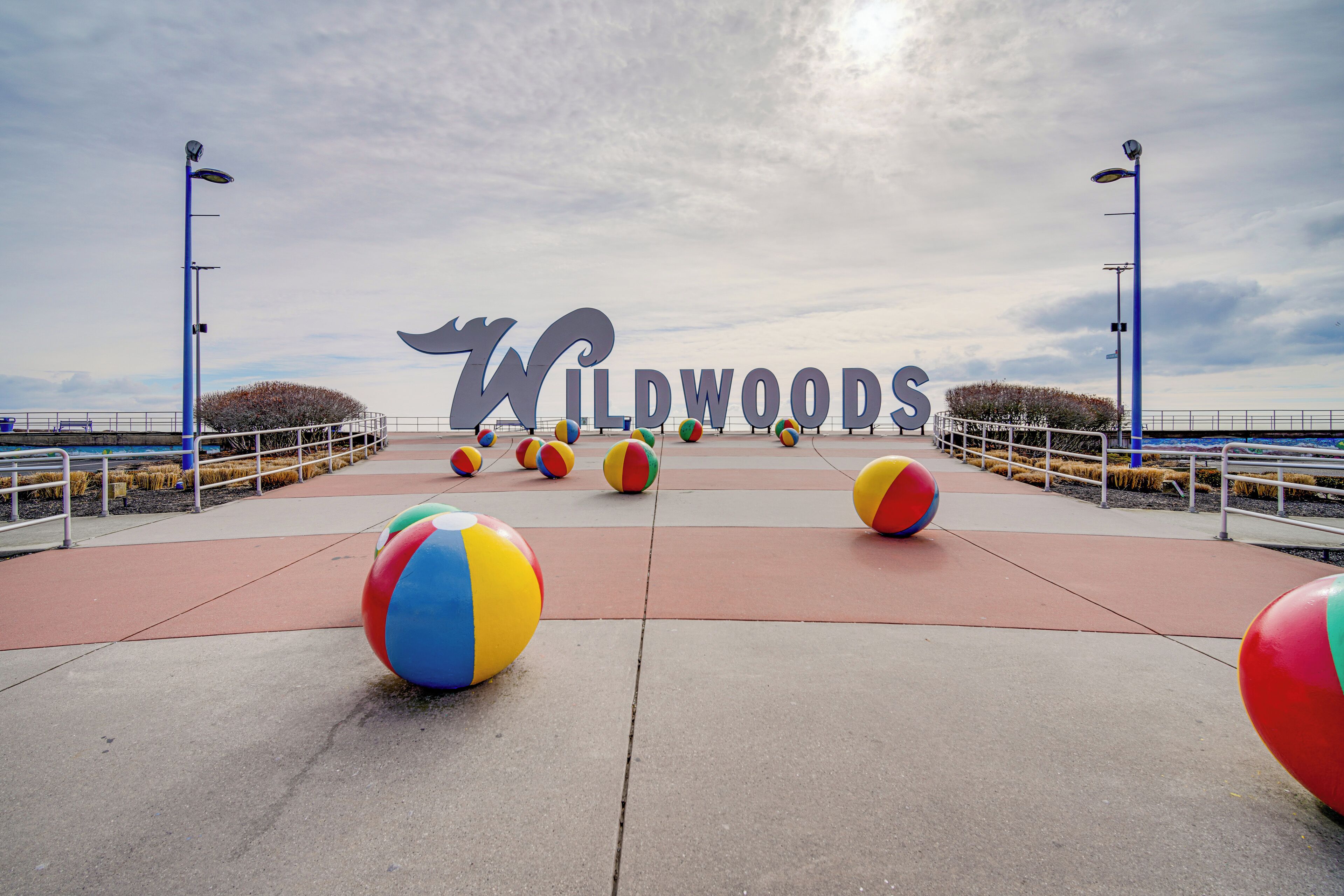 Um calçadão com uma grande placa 'Wildwoods', bolas de praia e um corrimão.