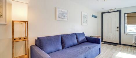 Una sala moderna con un sofá azul, una estantería escalonada de madera y un ventilador de techo.
