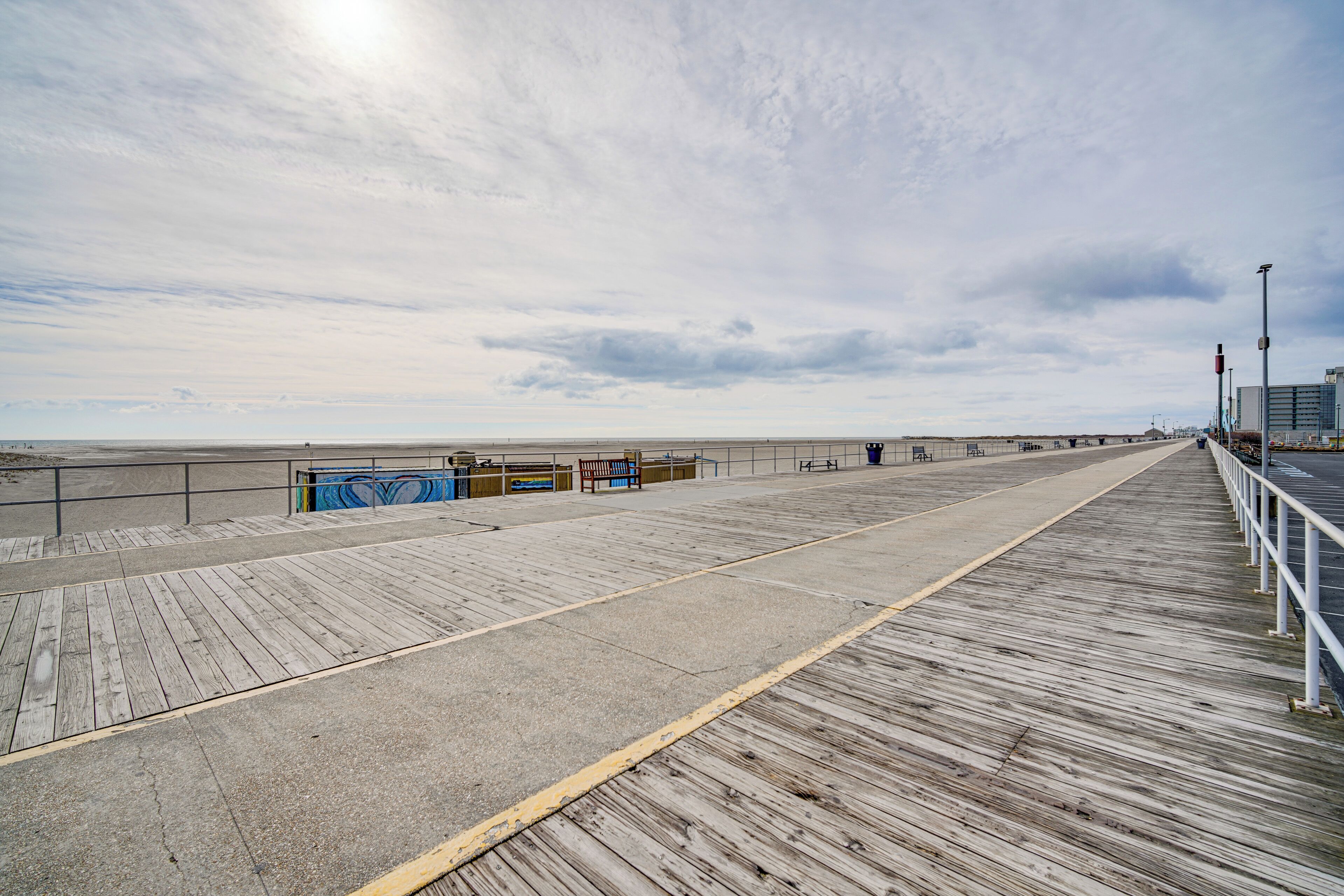 A wooden boardwalk leading to a beach with a clear sky.