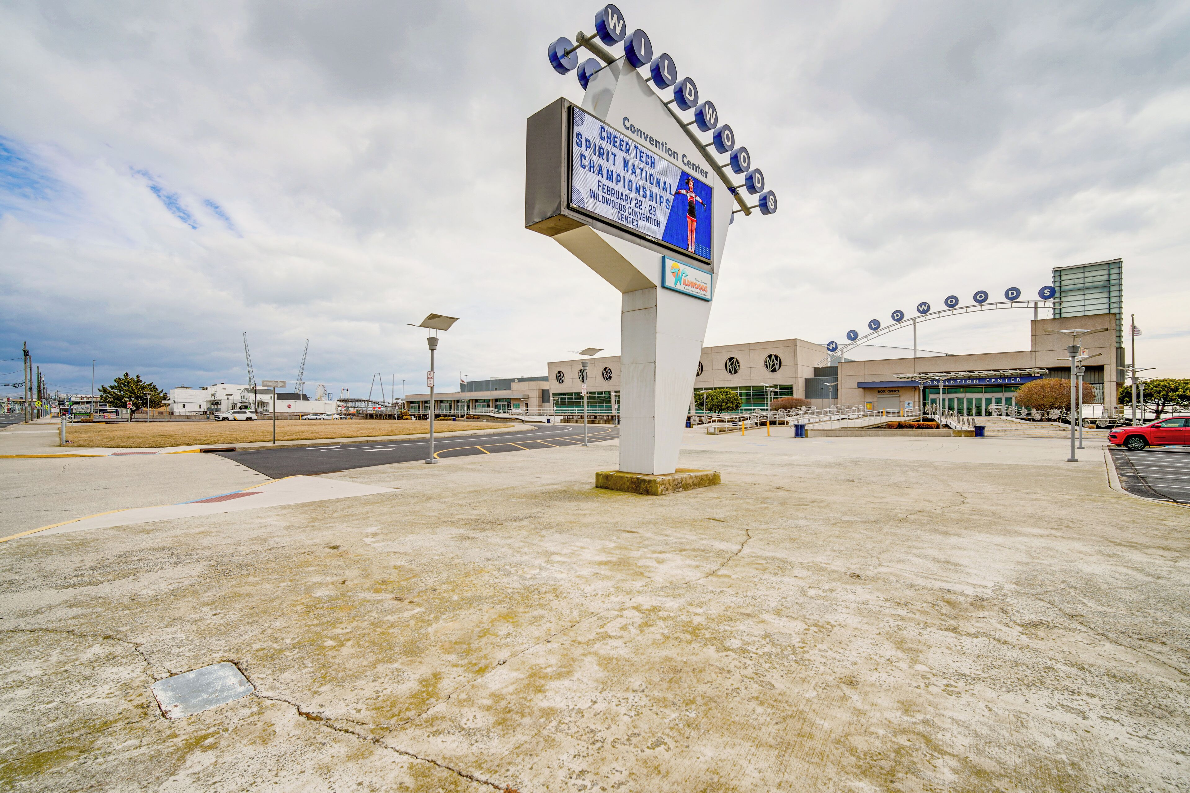 A convention center sign with a large display and a building in the background.