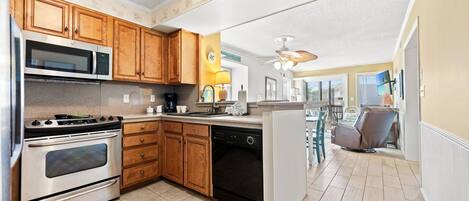 A kitchen with wooden cabinets, stainless steel appliances, and a view to a dining area.