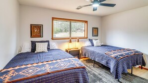 A bedroom with two beds, a ceiling fan, a window, and a nightstand. - Premier Trout Fishing: Scenic White River Cabin (Lakeview)