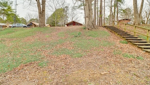 A cabin with a wooden staircase leading up to it, surrounded by trees and a grassy area with fallen leaves. - Premier Trout Fishing: Scenic White River Cabin (Lakeview)
