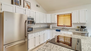 A modern kitchen with white cabinets, stainless steel appliances, granite countertops, and a window with blinds. - Premier Trout Fishing: Scenic White River Cabin (Lakeview)