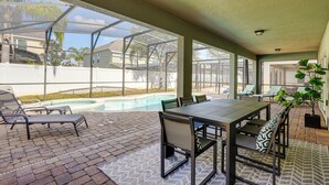 A covered patio with a pool, outdoor seating, and a view of the neighborhood.