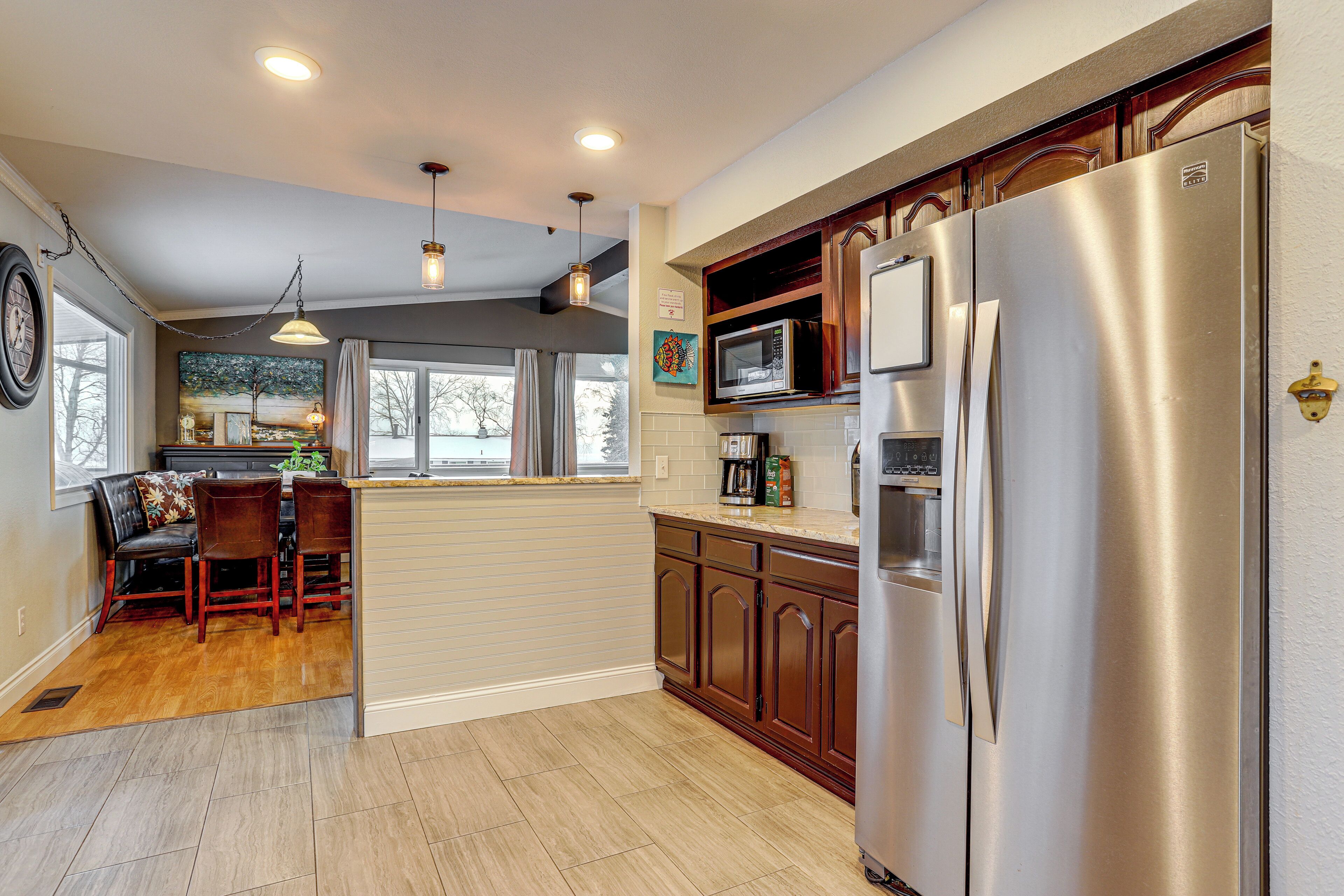 A kitchen with wooden cabinets, stainless steel appliances, and a dining area with a table and chairs.