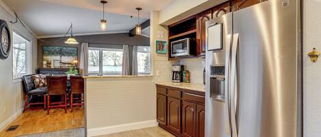 A kitchen with wooden cabinets, stainless steel appliances, and a dining area with a table and chairs.