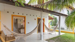 A covered outdoor area with a hammock, a sofa, and a staircase leading to an interior room.