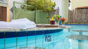 A pool area with a 'Stay Hall' sign, a towel, a cup, and a flower arrangement.