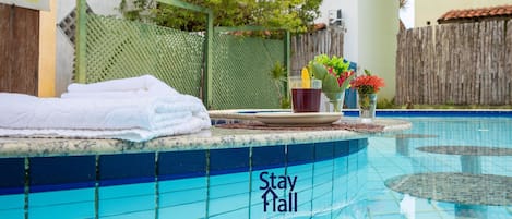A pool area with a 'Stay Hall' sign, a towel, a cup, and a flower arrangement.