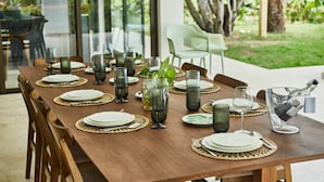 Une table à manger dressée pour six personnes, avec assiettes, couverts et verres, entourée de chaises.