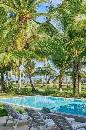 A pool area with lounge chairs and palm trees.