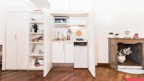 A compact kitchen with white cabinetry, a microwave, and a small dining area.