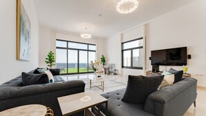 Una sala de estar moderna con un sofá gris, una mesita y un televisor.