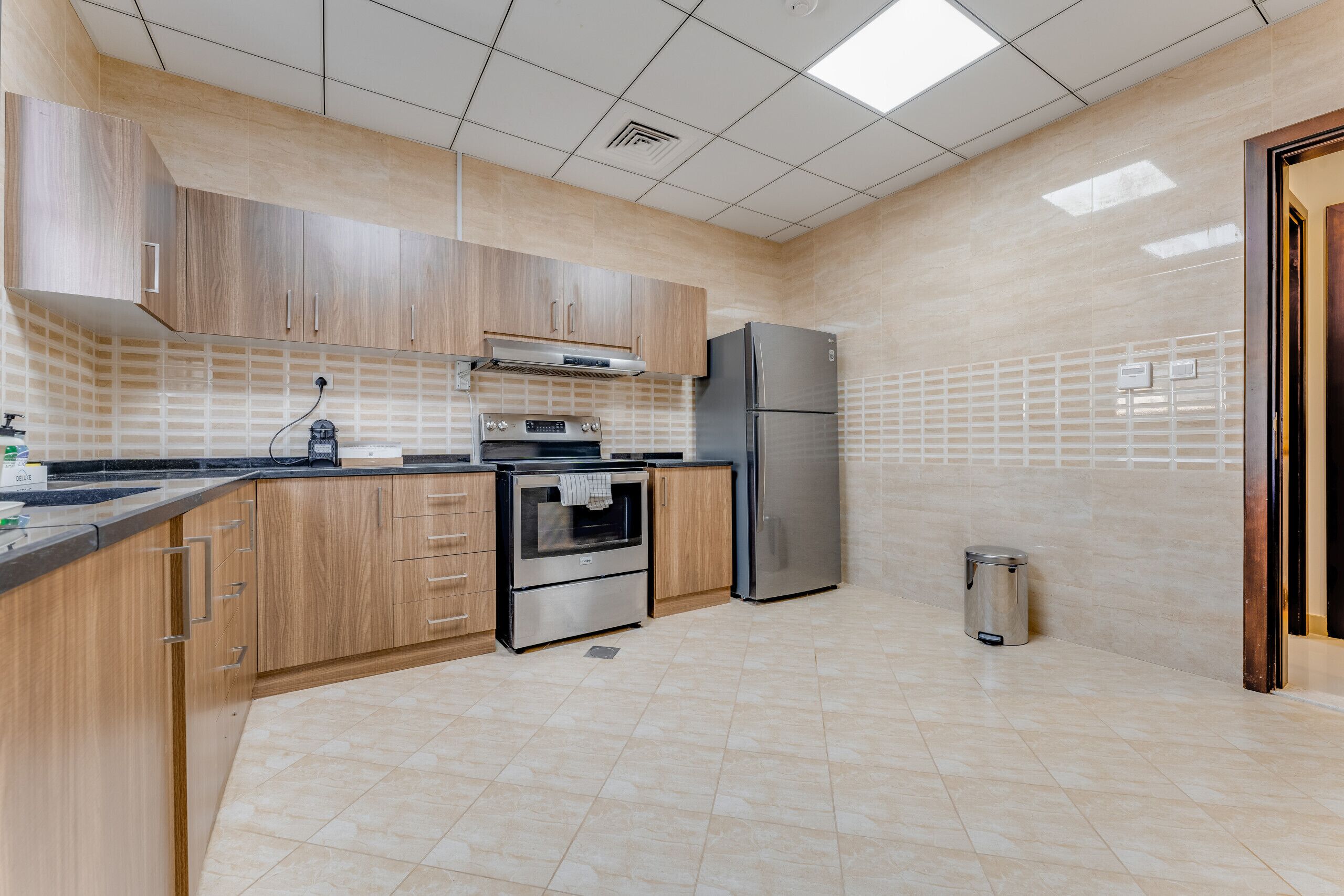 A modern kitchen with wooden cabinets, stainless steel appliances, and a tiled backsplash.