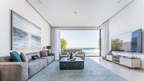 Ein modernes Wohnzimmer mit einer großen Couch, einem Couchtisch und einem Fernseher auf einem Lowboard.