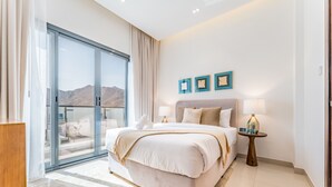 Ein modernes Schlafzimmer mit einem großen Bett, einer Glastür, die auf einen Balkon führt, und Bergblick.