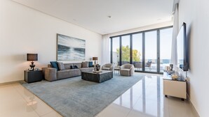 Ein modernes Wohnzimmer mit einer Eckcouch, einem Couchtisch und einem großen Fenster mit Blick ins Freie.