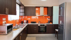 Een moderne keuken met donkere houten kastjes, een roestvrijstalen koelkast, een magnetron en een oven.