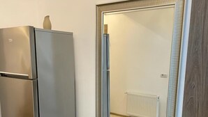 Une cuisine équipée d’un réfrigérateur en acier inoxydable, d’un meuble en bois et d’un miroir doté d’un cadre décoratif.