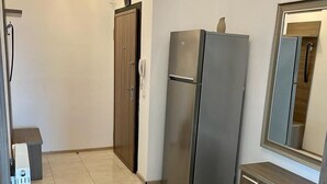 Une cuisine moderne avec un réfrigérateur en acier inoxydable, des armoires en bois et un sol carrelé.