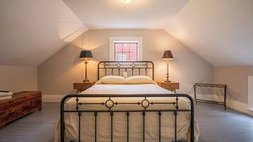 A bedroom with a bed, bedside lamps, a window, and a wooden dresser.