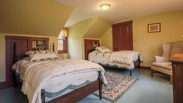 A bedroom with two beds, a wooden wardrobe, a chair, and a patterned rug.