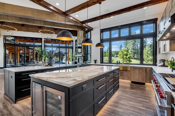A modern kitchen with a large island, black cabinetry, and stainless steel appliances.