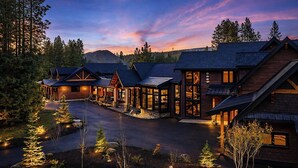 Ein modernes Lodge mit mehreren Holzhütten, einem zentralen Gebäude mit großen Fenstern und einer gut beleuchteten Auffahrt.