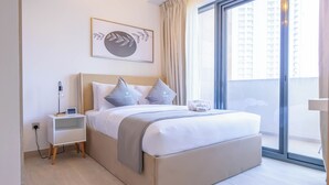 Un dormitorio moderno con una cama grande, una mesita de noche, un enchufe, una ventana con cortinas y una obra de arte enmarcada en la pared.