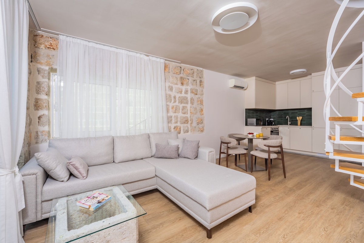 A modern living room with a sectional sofa, a glass coffee table, and a dining area with chairs.