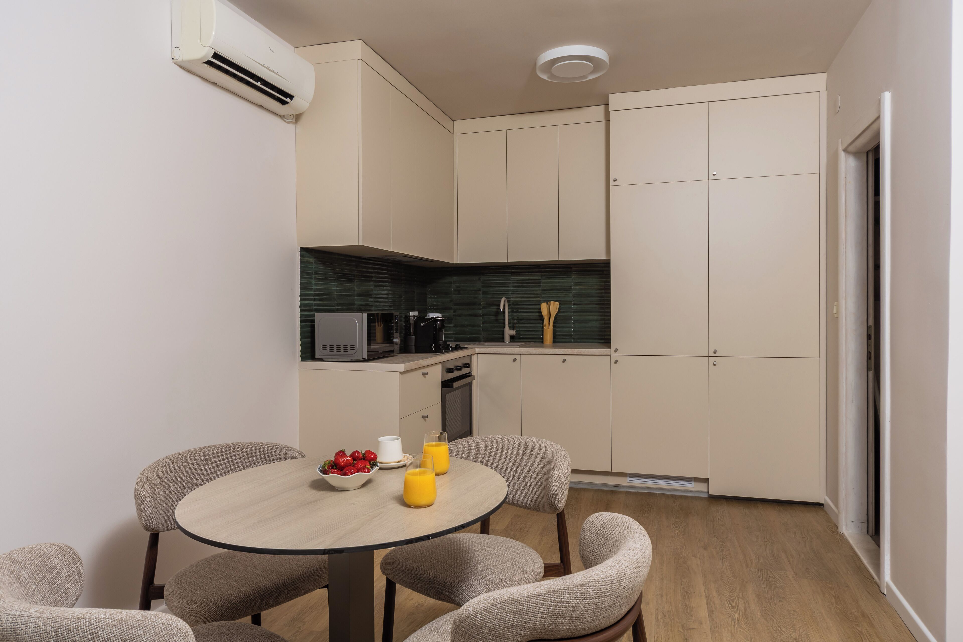 Cocina compacta con comedor, que incluye una mesa redonda con sillas, microondas, cafetera y tostadora.