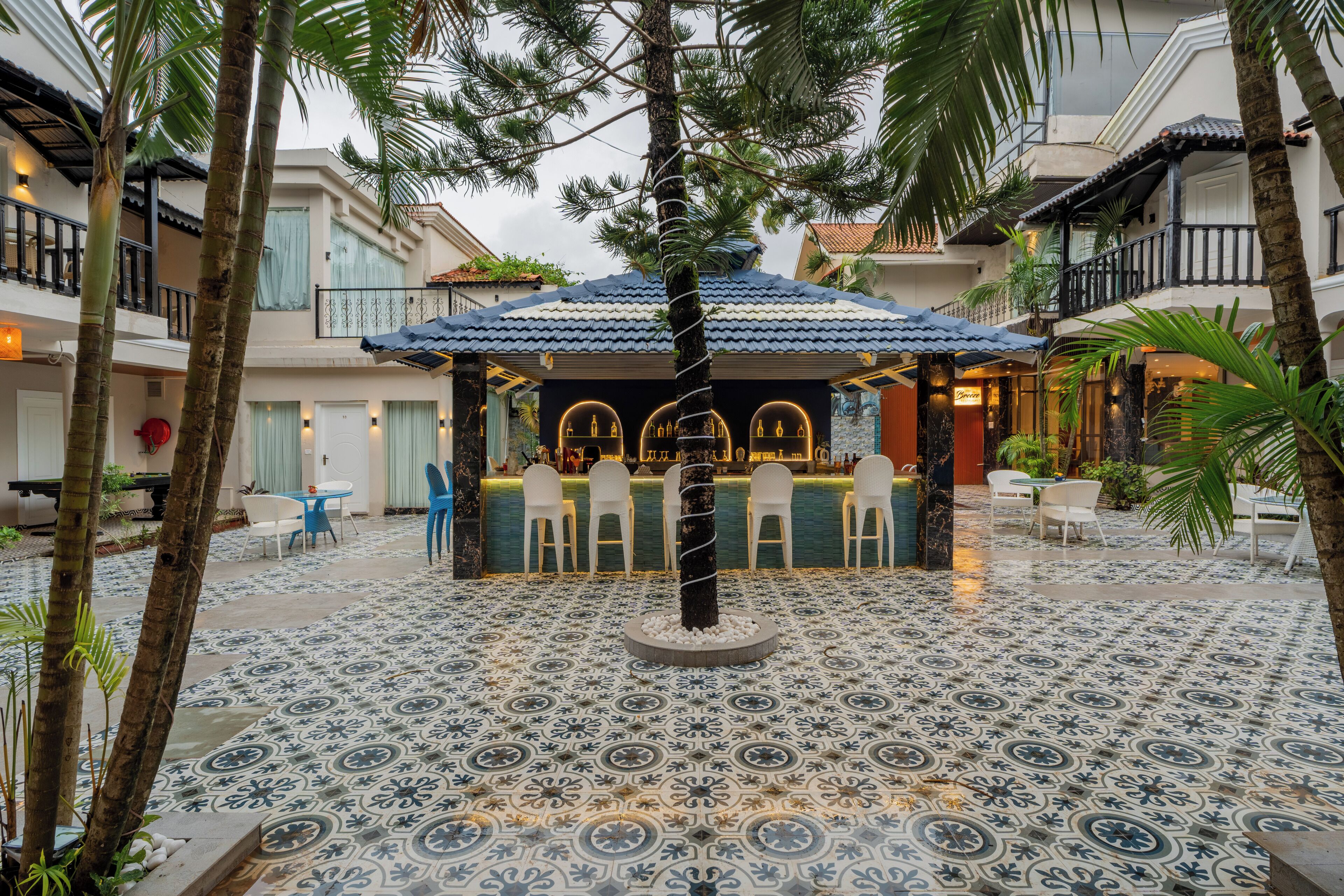 A courtyard with a bar area, palm trees, and patterned flooring.
