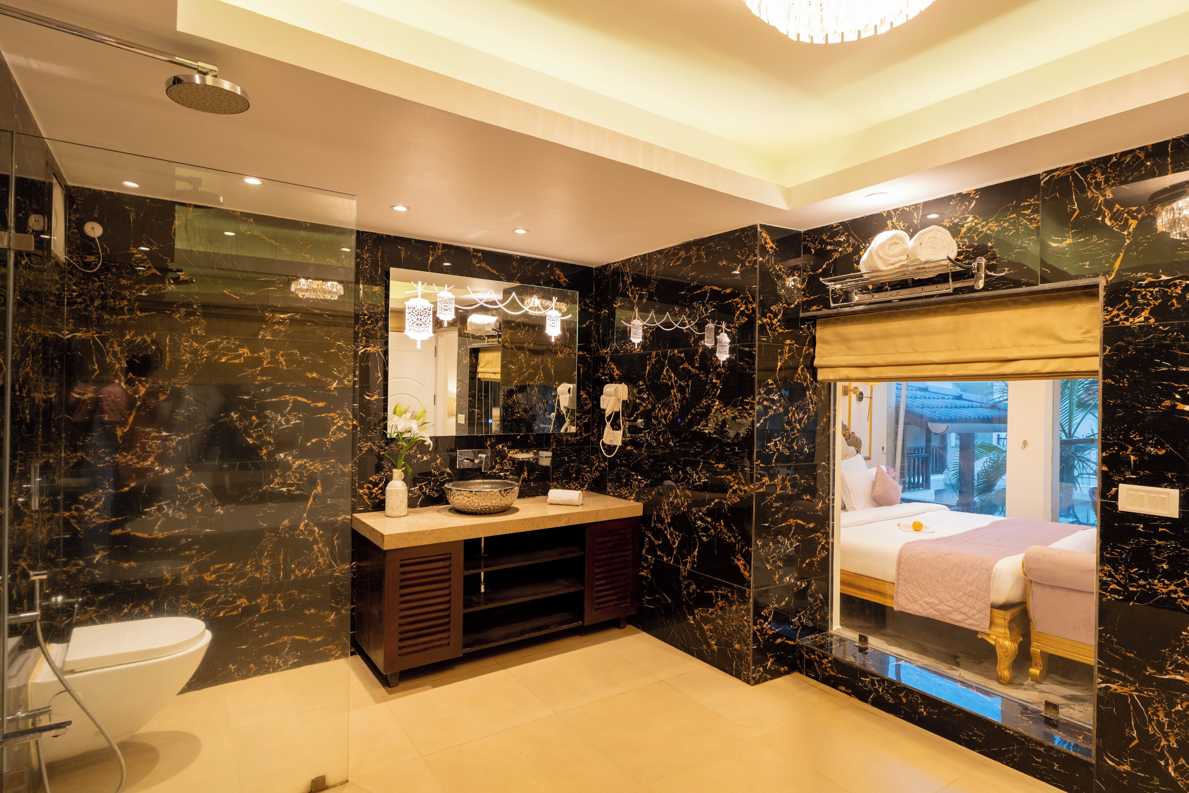 A modern bathroom with a glass-enclosed shower, a vanity with a bowl sink, and a bed with a view of the outdoors.