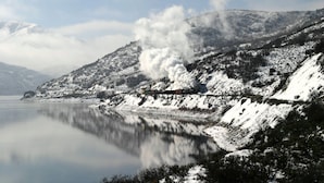 A snow-covered landscape with a lake and a train emitting steam. - Villa 2055 2 Queen Beds - 1 Bedroom 1 Bath No Kitchen 1 Villa (Midway)