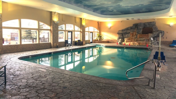 Una piscina interior con suelo de piedra, ventanas amplias y un mural en el techo.