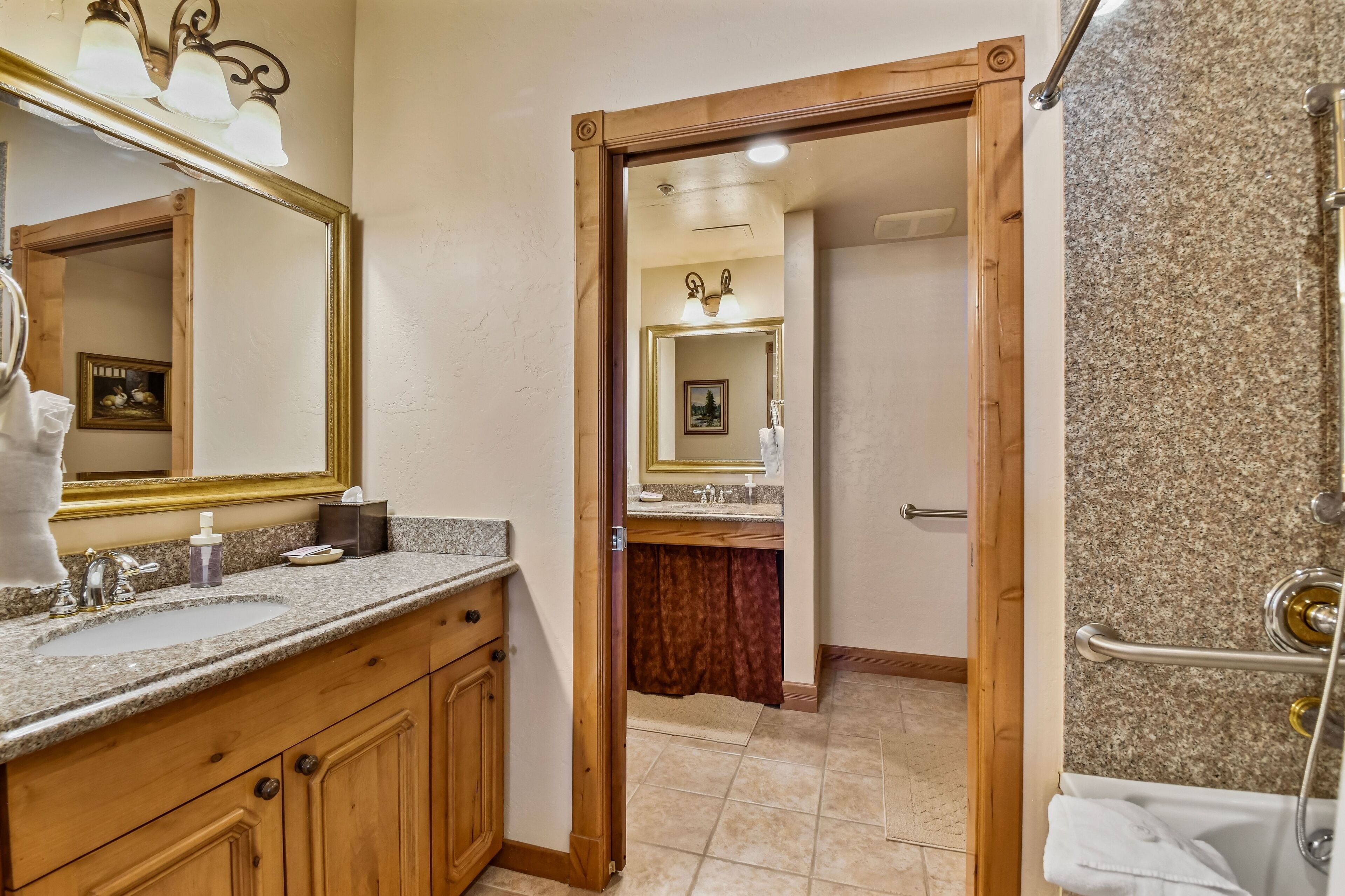 A bathroom with a wooden vanity, a large mirror, and a shower area.