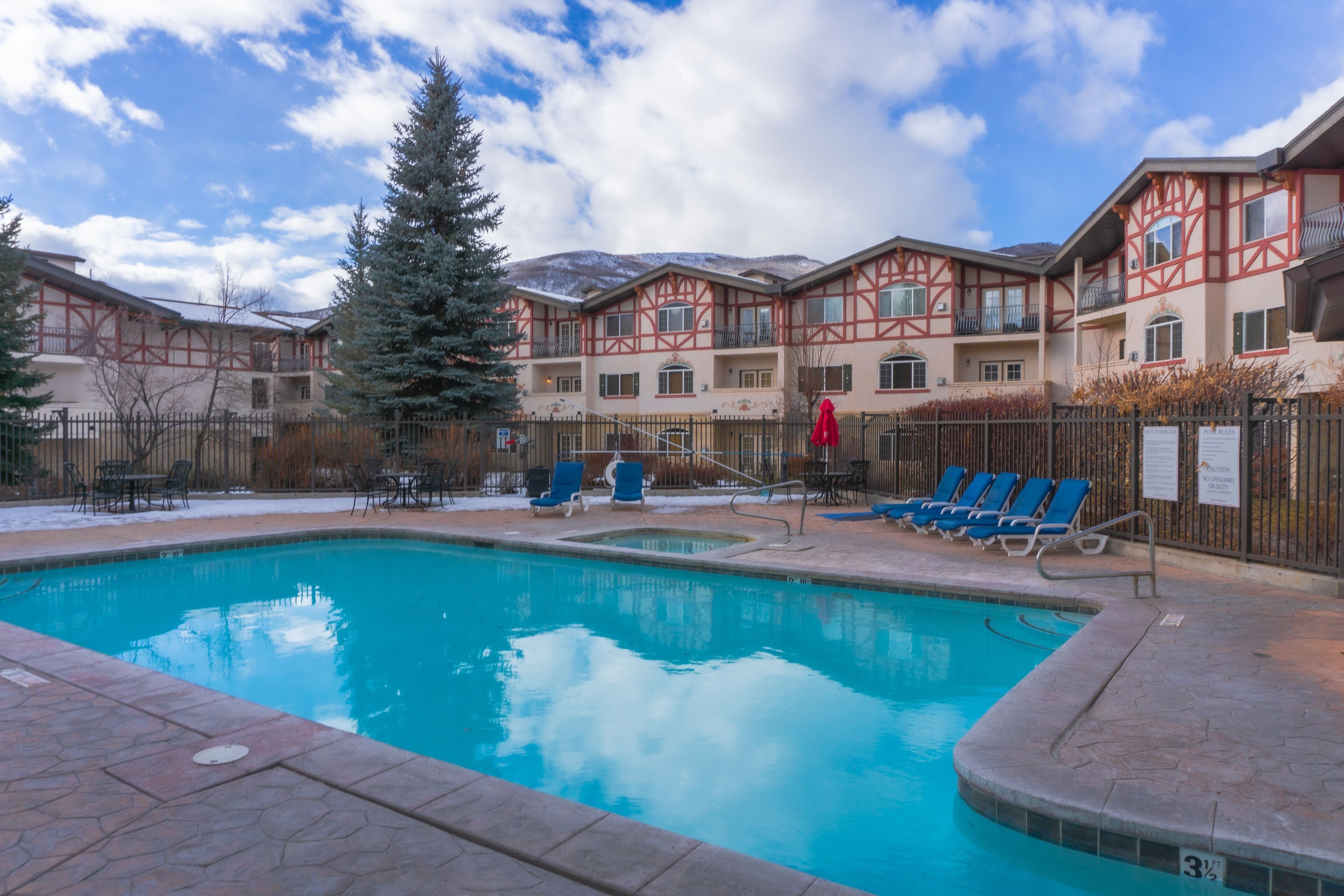 A swimming pool with lounge chairs and a building with a traditional architectural style in the background.
