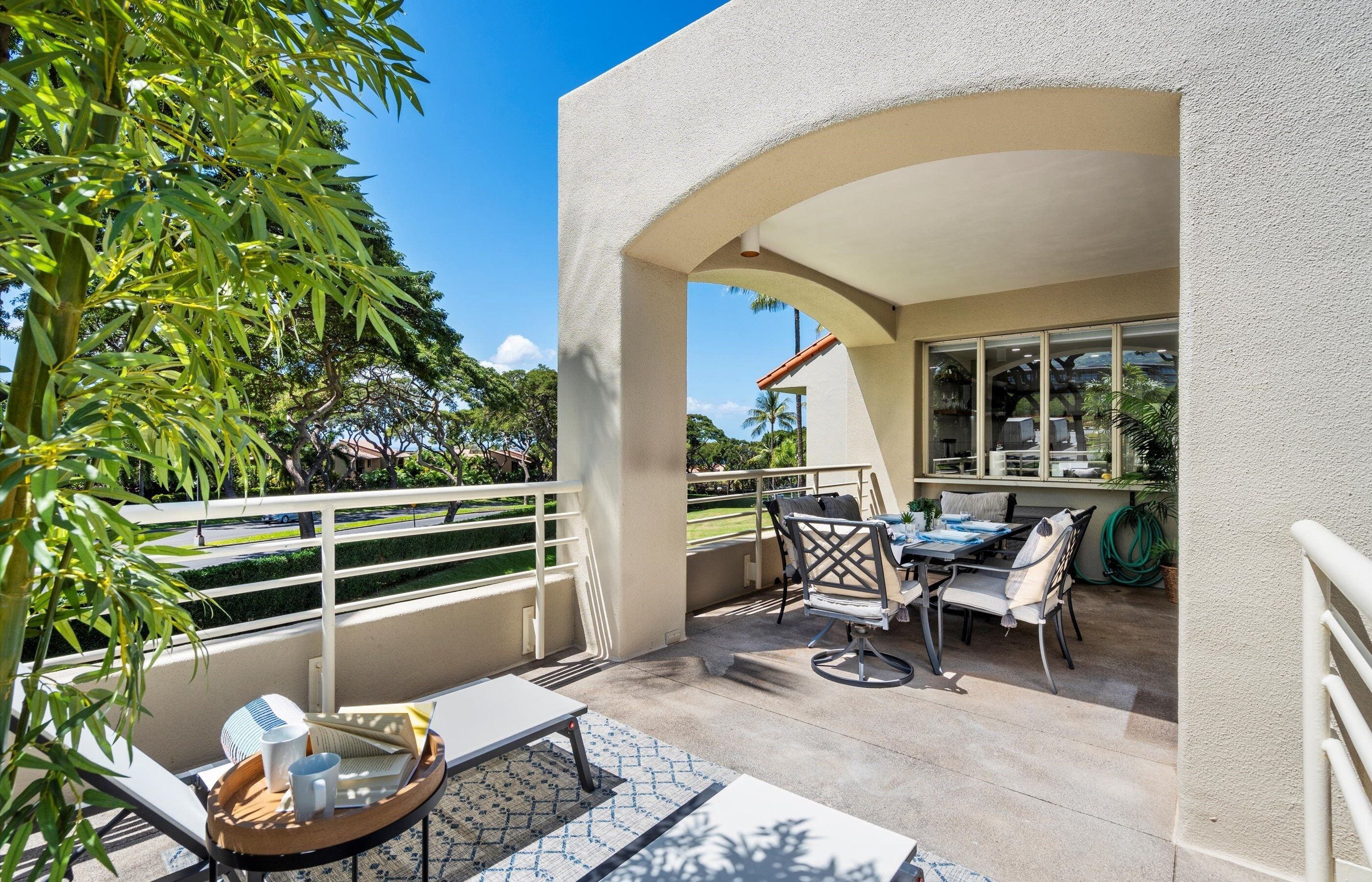 Un balcon avec une table et des chaises, une balustrade et une vue sur la verdure environnante.