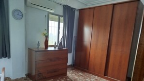 Een kamer met een houten garderobe, een dressoir, een klok en een raam met gordijnen.
