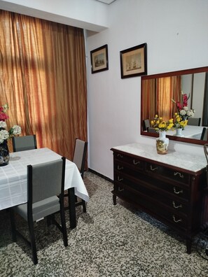 Un coin repas comprenant une table, des chaises, une commode en bois et un miroir.