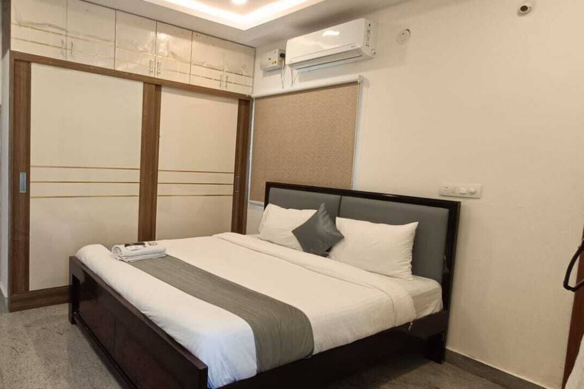 A bedroom with a bed, a wardrobe, and an air conditioning unit.
