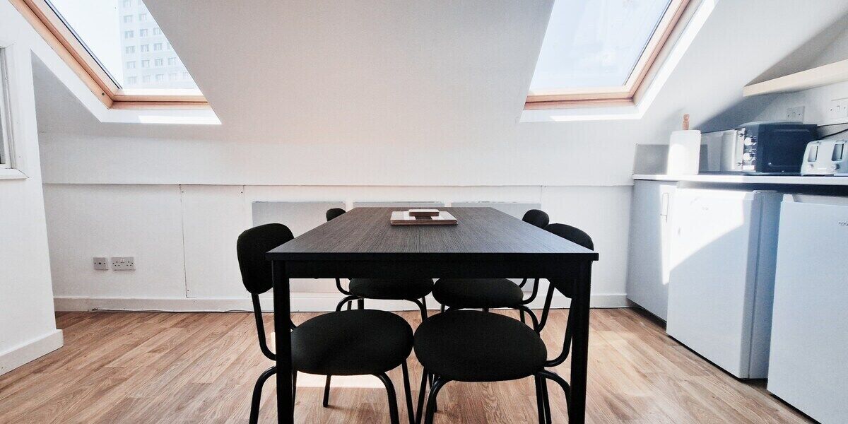 Une cuisine moderne avec une table en bois et quatre chaises, un réfrigérateur blanc et un four à micro-ondes.