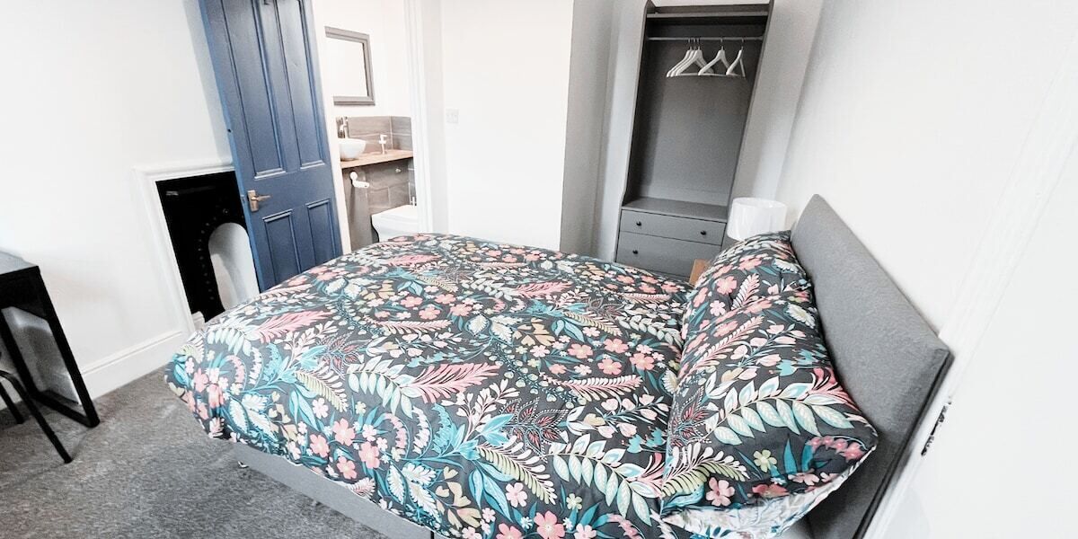 A bedroom with a bed, a wardrobe, and a small desk.
