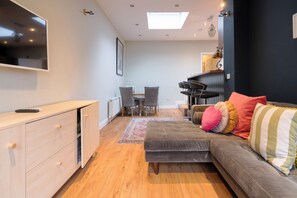 A modern living space with a sofa, a TV, a dining area, and a kitchen.