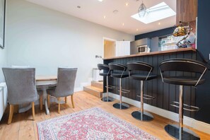 Une cuisine moderne dotée d’un plan de travail en bois, d’une table à manger avec quatre chaises et d’un coin bar avec des tabourets.